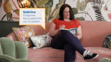Video-Standbild: Patientin sitzt auf Sofa und liest ein Buch
